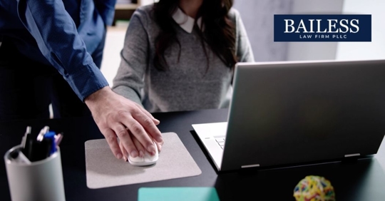 male boss putting his hand over a female employee's hand and leaning towards her desk